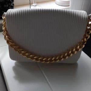 Vit väska - Vit väska. Ett stort fack, 3 mindre varav ena med dragkedja. Axelrem finns med. Helt ny, oanvänd.