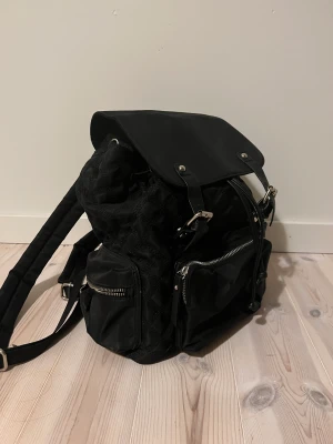 Ryggsäck - Bra förvaring med några innerfickor och flera på utsidan. Snygg och du får plats med dator och mapp men då kommer den inte gå att stänga helt men det funkar. Lite sliten på banden och hålen men det går