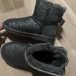 LÅGA UGGS - Oanvända glittriga uggs, mörkgrå färg, låga:) Köptes med från australien som present och var tyvärr för små och kan då inte lämnas tillbaka:/ Strl 37