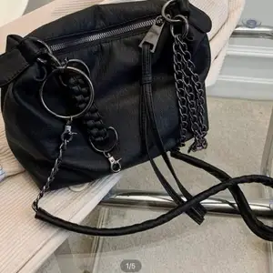 En svart läderväska från SHEIN som är helt oanvänd. Man kan ta bort kedjorna och använda som en necessär.