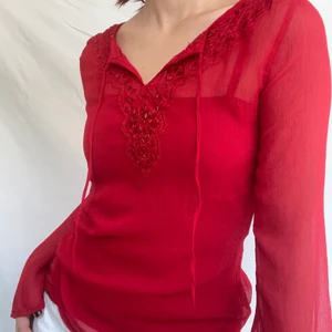 Pärlad fairycore röd blus - Fairycore topp med fina pärlade detaljer. Översta lagret är typ mesh och under det finns ett linne. Frakt tillkommer för 51kr. Plagget är i gott skick och visas på en storlek 38 (s)