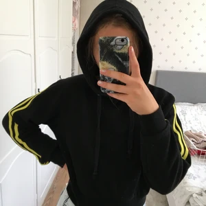 Svart hoddie med detaljer på ärmarna  - En svart hoddie med gula detaljer (linjer) på ärmarna, som Adidas fast två. Skitsnygg, verkligen finns inte mer så säljer bara vid bra bud! Men priset går att diskutera.
