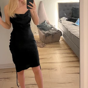 Klänning strl. XS - En svart klänning från Zara. Med snöre på sidorna, och waterfall effekt vid brösten. Den är väldigt tajt vid bysten, är ganska liten för sin storlek. Jag är 164 och på bilderna ser ni att klänningen går precis ovanför knäna. Aldrig använd, då jag ångra mig efter köp. Skriv för fler frågor! 200 kr + frakt🌸🌸
