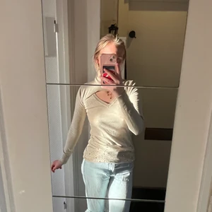 Beige polo tröja  - Så fin beige tröja med då många detaljer. Den är ganska lång men går att vika upp utan problem vid behov. Även fina små stenar längre ner på tröjan finns+ ett hål vid brösten med polo. Den är ganska tajt, vid halsen även kroppen. Från Emma & Ashley design. St finns tyvärr int men skulle säga att den är en S. 