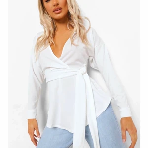 Långärmad omlottblus med knytdetalj - En vit Långärmad omlottblus med knytdetalj i midjan. Nyskick, använder ej på grund av inte min stil längre. Storlek 36 men passar även bra som 34. (34/36). Original pris 270.