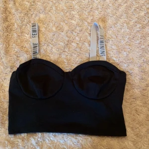 Bershka - Svart top med två vitta band som det står feminine på med svart text