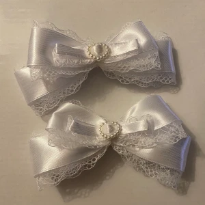 Vita hårrosetter  -  handgjorda vita hårrosetter i spets och satin, dekorerade med pärlhjärtan (plast). Kommer självklart i par och ser super fina ut i håret med tvintails och andra frisyrer!