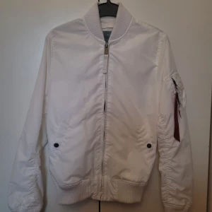 Alpha industries bomberjacka vit - Bomberjackan är ifrån alpha industries och är helvit första bilden är utan ijus så som jackan ser ut klarvit resten av bilderna är det stark lampa i bakgrunden. Den är i bra skick i storleken S. Köparen står för frakten. 