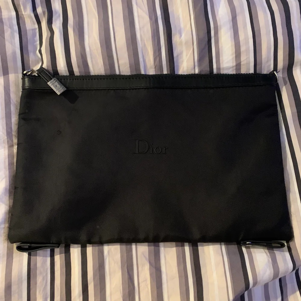 En dior pouch väska i 10/10 skick med svart diortext på framsidan, den är köpt i diorbutiken i köpenhamn. Skriv om trade. Priset är ej hugget i sten då jag vill bli av med dem pga använder den inte.. Väskor.