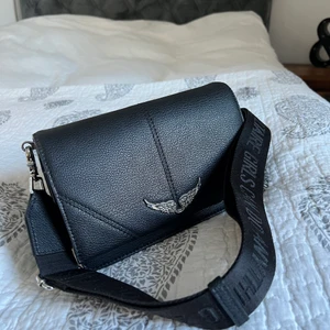 Väska från Zadig & Voltaire  - Svart väska som är köpt i deras butik i London. Ser som ny ut och är knappt använd. Varför den inte har används så mycket är för att den gick sönder i väskbandet precis när jag köpt den. Har gjort en lösning hos en skomakare för det gick inte att fixa på ett annat sätt. Skriv privat för bilder på lösningen av väskbandet. Budgivningen startar på 1000kr. Nypris 3700kr. Frakten ingår inte i budpriset.