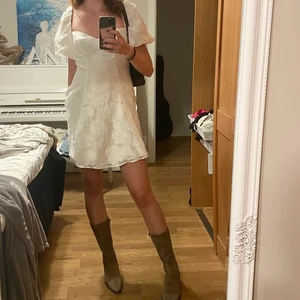 NA-KD klänning strl 38 - Studentklänning i nästan nytt skick, (har använts en gång). Vitt, skimmrigt tyg med broderade blommor/blad. Ser väldigt lyxig ut, prinsessa-vibe <3