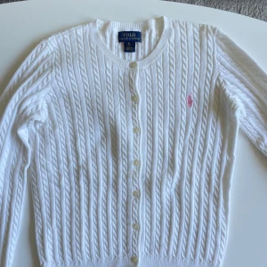 Ralph Lauren kofta - Vit kabelstickad kofta från Ralph Lauren kids i storlek XL 16 years (motsvarade storlek XS). Pris 200 kr eller högstbjudande. Mycket fint skick, nästintill oanvänd.