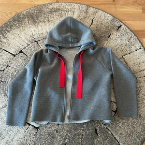 Gråkofta  - Gråkofta med röda band från Work out. Storlek: 36 