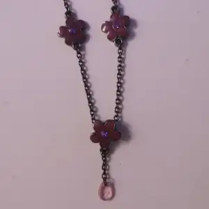 Fint halsband med mörk kedja, lila blommor. Från tidigt 2000-tal. Köpt på plick. Kan alternativt skicka som brev för 15 kr. 
