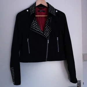 gina tricot bikerjacka strl M  - jacka i svart tyg från Gina Tricot strl M, jag har strl 34, så den är lite oversize på mig. Fattas två nitar på kragen i nacken. 