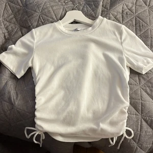 Topp med knyten - Vit ribbad topp från zara men knyten vid sidan. Säljer då den inte kommer till användning. Nyskick, storlek M