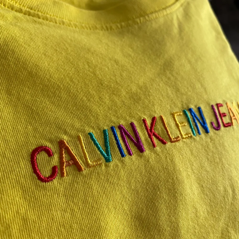 En superfin gul Calvin Klein T-shirt, med regnbågsfärgat broderat märke på! Använd 2 gånger, i nyskick, inga defekter ✨ fler bilder finns. T-shirts.