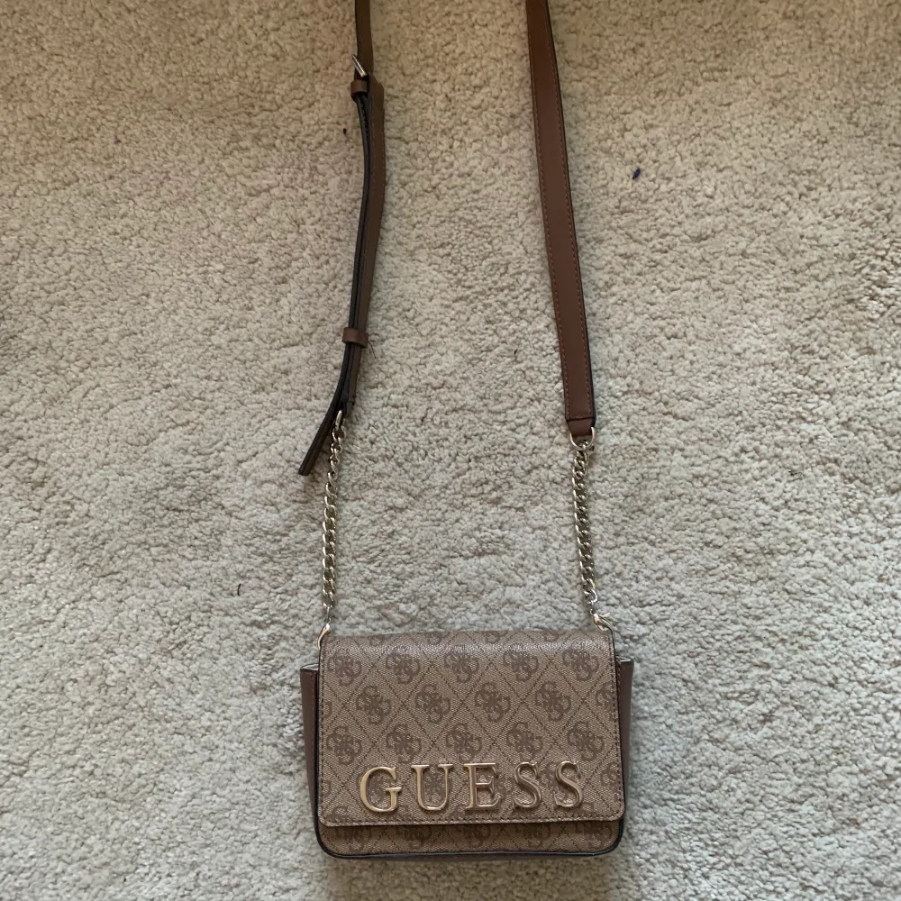 En brun Guess Handväska  , är köpt för några år sedan men kommer inte till användning längere 💗  den är äkta  pris kan diskuteras . Väskor.