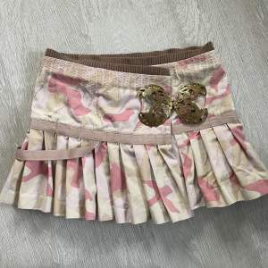 Perfekta vintage y2k kjolen från märket Munthe plus Simonsen💓 Rosa camo mönster, plisserad och har coolt fjärilsspänne och andra snygga detaljer🌸 Storlek på lappen är eu34, men skulle säga närmare 36, se mått: 39cm platt midja, 34cm längd🌟