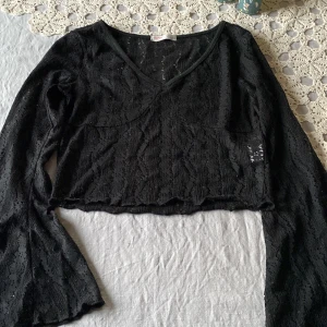 Svart cropped spetstopp  - En svart cropped spetstopp med vida armar i storleken xs. Tröjan är lite knoppig (ses på bild)  