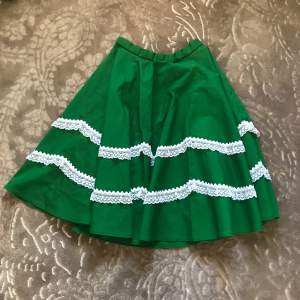 Handgjord grön kjol med vit spets!  31 cm i midjan och 61 cm i längden. Kjolen är i fint skick!💕