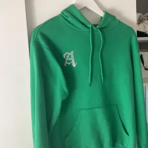 Grön hoodie med ett A av strasstenar, har satt på stenarna själv