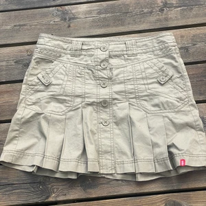 Kjol - En militär grön/grå kjol, man kan ha den som low waisted och high waisted/mid. (Har aldrig använt den)