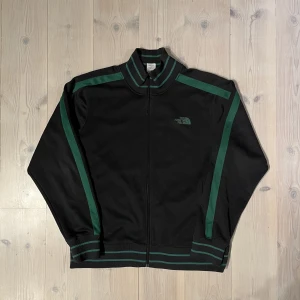 The north face tracktop - En riktigt snygg track-top till en bajare. Storlek L fitten påminner om needles och Palm angels. Riktigt bra skick utöver att själva grejen man drar ner i dragkedjan ramlat av men det går nog lätt o fixa med ett gem eller likande. 