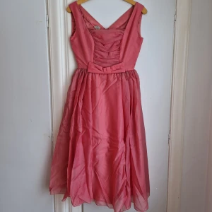 Vintage rosa festklänning  - Fantastiskt fin klänning med allt man kan önska! Tyl och vidd i kjolen.  Effektfullt rynkad framtill. Lätt v- ringning i ryggen.  En lätt ångning skulle ge den sin gamla glans åter! Sen är den redo för bröllop eller andra festligheter. M/L/42/44