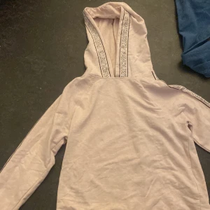 Hoodie  - En rosa hoodie med text på armarna 