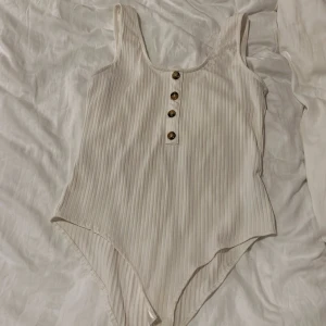 vit body - Vit body med knappar från HM.  Djur finns i hemmet, köparen står för frakt. ☺️