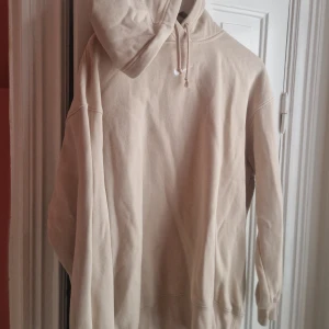 Beige hoodie Nike - Stilren beige hoodie från Nike i storlek M. Tröjan har huva med snörning och är tillverkad i mjuk bomullsmix. Perfekt för dig som gillar en clean och avslappnad look. Klassisk Nike-logga broderad på bröstet. 