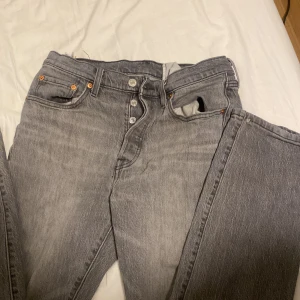 Grå Levi's 501 jeans W29 L32 - Säljer ett par grå Levi's 501 jeans med klassisk rak passform och knappgylf. Jeansen har fem fickor, snygga kontrastsömmar och den ikoniska läderpatchen bak. Perfekt tvättad grå färg som ger en cool vintage vibe.