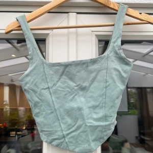 Ljusgrön linnetopp med breda axelband - Snygg ljusgrön linnetopp med breda axelband och figurnära passform. Toppen har en enkel, stilren design och är tillverkad i mjuk bomull. Perfekt att matcha med jeans eller kjol för en fräsch look.