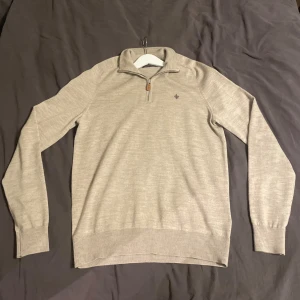Beige merinoullströja Morris half zip - Säljer en beige stickad tröja från Morris i 100% merinoull. Tröjan har half zip med läderdetalj, liten broderad logga på bröstet och ribbade muddar. Perfekt för lager-på-lager och snygg till jeans eller chinos. Inga hål fint skick!