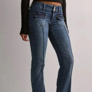 Blå bootcut jeans med fickdetaljer  - Snygga blå jeans med bootcut passform och markerade sömmar längs benen. Framtill finns två stora fickor med lock och knapp, samt klassiska bakfickor. Använt max 6 gånger!🥰köpte de för 699kr