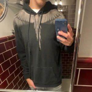Svart Marcelo Burlon hoodie - Snygg svart hoodie från Marcelo burlon med grå vingar. Är perfekt för kyligare dagar och passar perfekt för att lager på lager. Är 181 och jag bär vanligtvis s-m. Om du har några funderingar tveka inte på att höra av!