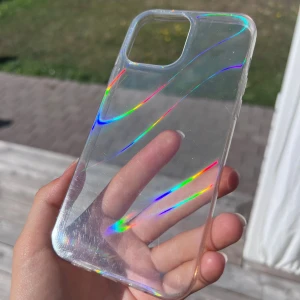 Transparent mobilskal med regnbågseffekt - Ett genomskinligt mobilskal som passar till iPhone 13 Pro Max. När ljuset träffar skalet skimrar/blänker det i regnbågsfärger 💛💚❤️ Syns bäst i direkt solljus! Använt max 3 gånger.