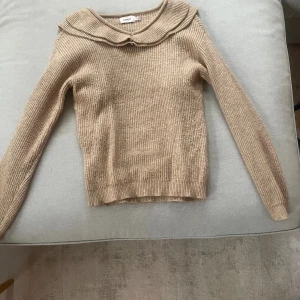 Beige stickad tröja med volang från ONLY - Supersöt beige stickad tröja från ONLY med volangdetaljer längs axlarna och runt kragen framtill. Jättefin nu till hösten och nkel att matcha med både jeans och kjol🥰