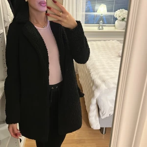 Svart teddyjacka  - Mysig svart teddyjacka lång ärm. Jackan har en oversized passform och är tillverkad i ett fluffigt teddy-material som håller dig varm. Perfekt för dig som gillar en chill och trendig look. Enkel att matcha med både jeans och mjukisbyxor! Knapparna har dock gått av