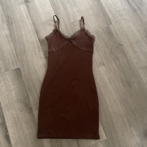 Brun ribbad kortklänning från H&M Divided - Supersöt brun ribbad kortklänning från H&M Divided i storlek XXS. Klänningen har tunna axelband, spetsdetaljer vid bysten och längs urringningen samt en figurnära passform. Perfekt för dig som gillar en enkel men ändå snygg stil.❤️