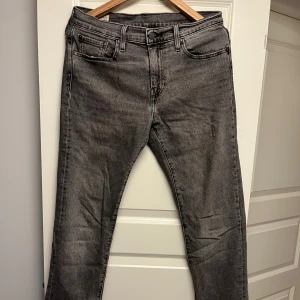 Grå Levi's 502 straight fit - Snygga grå jeans från Levi's Premium med klassisk femficksdesign och raka ben. Jeansen har en stilren look med svarta sömmar och läderpatch bak i midjan. Perfekta för dig som gillar en enkel och clean stil. Nypris: 1149, mitt pris: 549. Storlek: W30 L34.