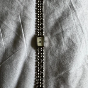 D&G Time silverfärgad klocka - Stilren klocka från D&G med rektangulärt ur och coolt armband i rostfritt stål. Klockan är silverfärgad med minimalistisk urtavla och D&G-logga. Armbandet består av flera rader med blanka, runda länkar som ger en unik look.