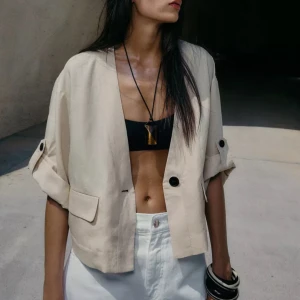 Beige croppad overshirt  - Snygg beige croppad overshirt med v-ringning, korta ärmar med knappdetalj och en enkel knapp framtill. Använd 1 gång. Pris kan diskuteras.