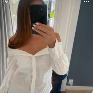 Vit offshoulder blus - Säljer en vit offshoulder blus med långa ärmar och knappar framtill. Klänningen har en luftig och lätt känsla, perfekt för varmare dagar. Stilren och enkel design som ger en fräsch look. Säljer då den sitter lite litet på mig. Finns några få tecken på att den varit använd men inget man tänker på 