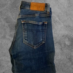 Tiger Of Sweden - Snygga mörkblå slim jeans från TOS med klassisk femficksdesign och läderpatch bak i midjan. Jeansen har slim passform och är tillverkade i stretchigt denim för extra komfort. Perfekta för dig som gillar en slim look och stilrena detaljer.