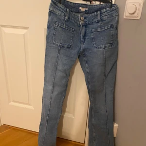 Ljusblå bootcut jeans Gina Tricot 164 - Snygga ljusblå jeans från Gina Tricot i storlek 164. Modellen har bootcut-ben, hög midja och stora framfickor. Klassisk jeanslook med synliga sömmar och bekvämt material i bomull. Perfekta för en trendig och avslappnad stil.