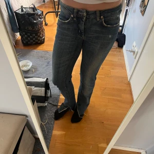 Blå Acne Jeans bootcut - Säljer ett par klassiska blå jeans från Acne Jeans med snyggt slitna detaljer och bootcut-modell. Jeansen har fem fickor, normal midja och är tillverkade i bomull. Perfekta för dig som gillar en tidlös och avslappnad stil.