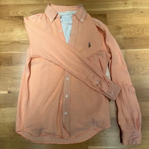  skjorta från Ralph Lauren - Persikofärgad skjorta från Ralph Lauren med klassisk krage, knappar framtill och broderad logga på bröstet. Skjortan är i storlek S passar XS,😀perdekt för en fin utekväll med vänner eller familj🍾skriv vid minsta fundering!♻️
