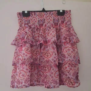 Rosa volangkjol med mönster - Supersöt volangkjol i rosa toner med blommigt och paisleyinspirerat mönster. Kjolen har flera lager volanger och smock i midjan för en bekväm passform. Kjolen är i storlek 158/164 men passar mig som har S💞